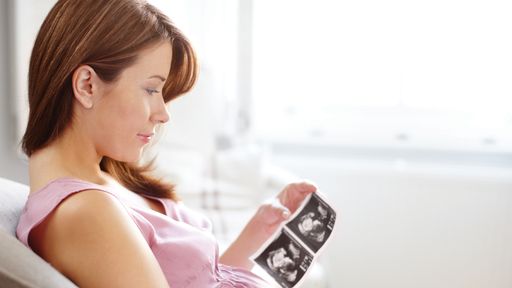 mujer embarazada observando una imagen ultrasonido del feto.