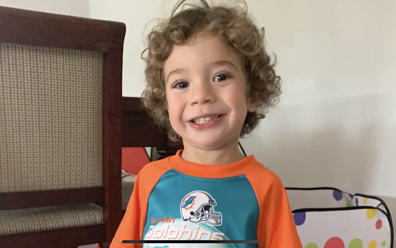 Ezra wearing a dolphins football shirt smiling for the camera.