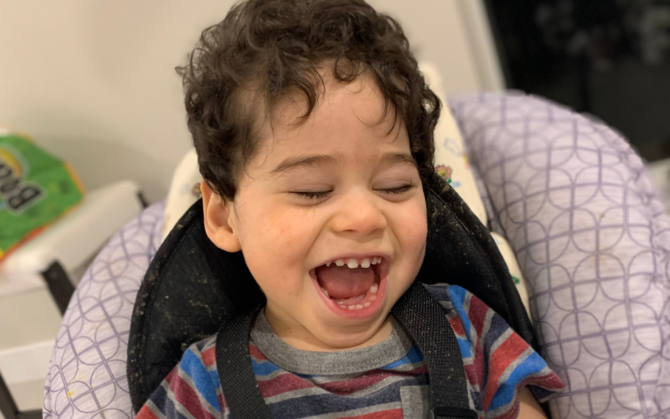 Bradley sitting in a car seat with a big smile. 