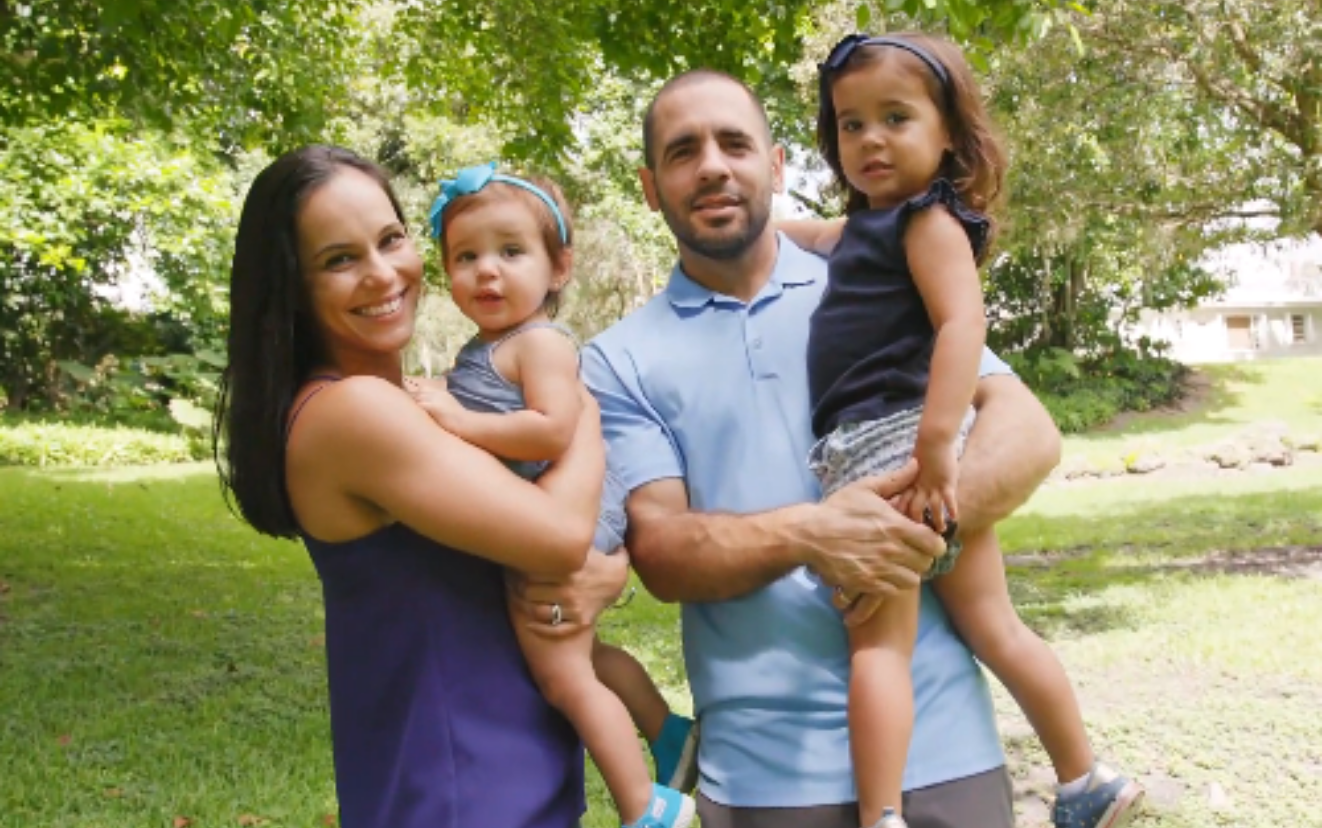 Mariana outside carried by her parents and next to her sister. 