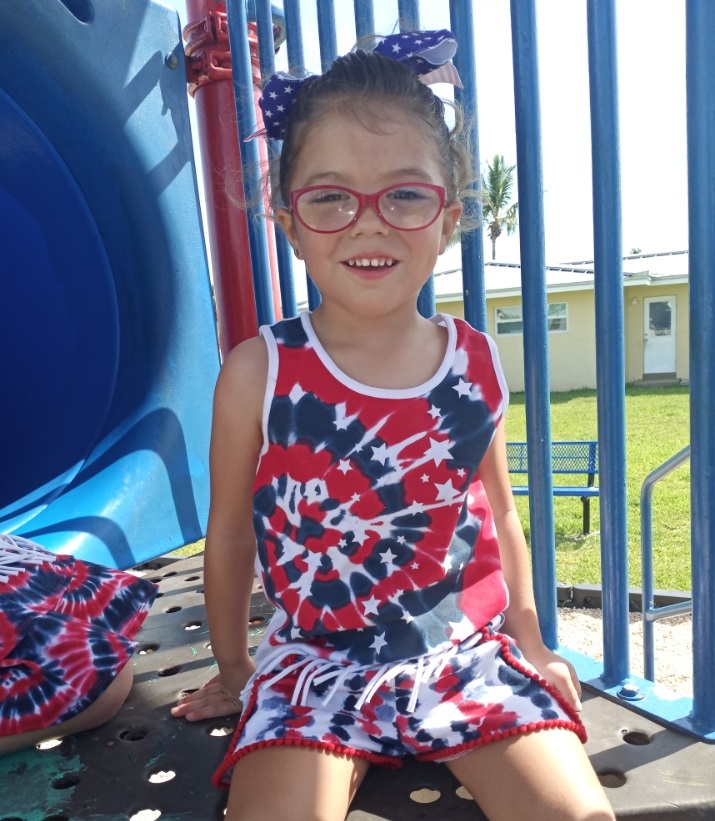 Athena, smiling for the camera while sitting in a park playground slide.