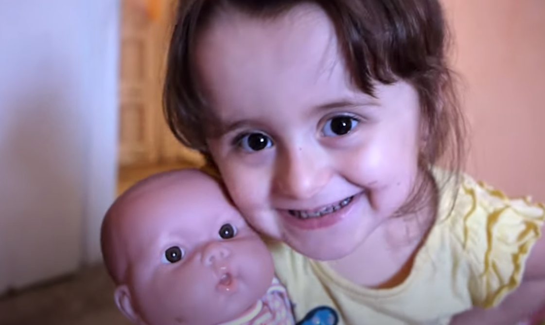 Alexis smiling while holding a baby doll. 