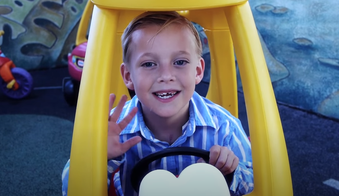 Nathan jugando en un coche de juguete en la sala de juegos del hospital.