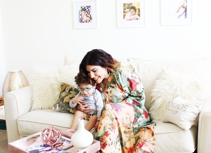 A mother sitting on a couch with her infant baby in her arms