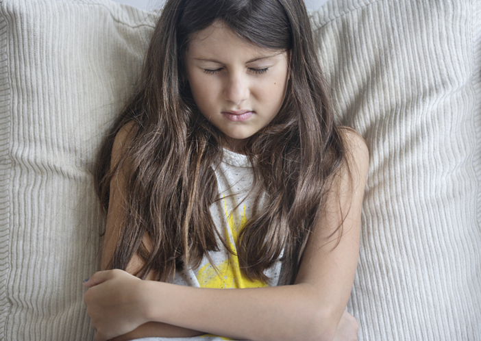 A young girl in pain holding their stomach