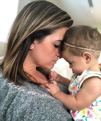 A mother resting her forehead gently against her infant daughter’s forehead 