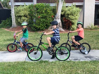 Three children riding bikes smiling