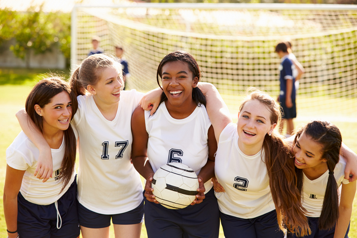 A women's soccer team posing in front of a goal 