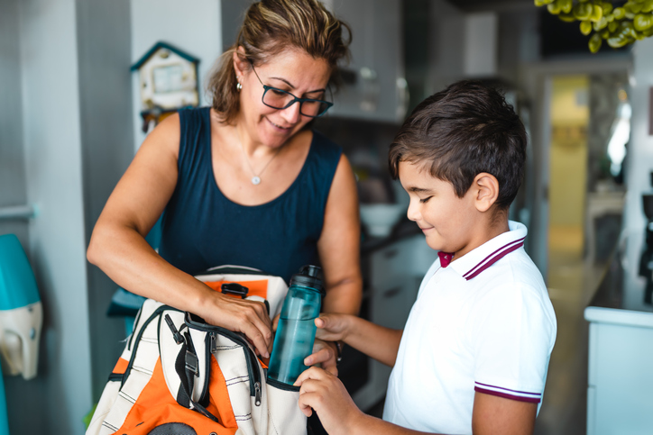 Mamá ayudando a su hijo a prepararse para la escuela