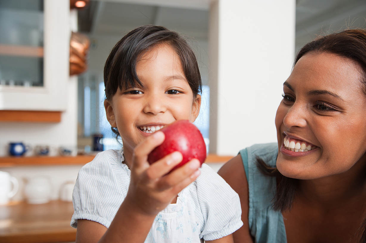 A smiling child holding an apple