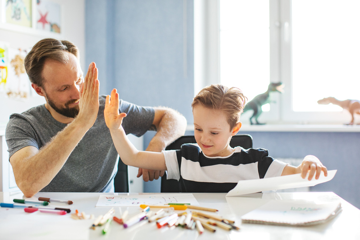 A father reviewing his son’s grades giving a high five