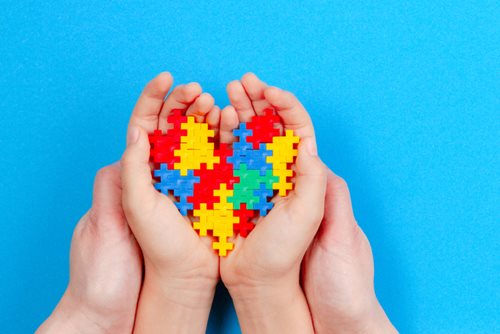 A puzzle heart being held in a child and parents hand