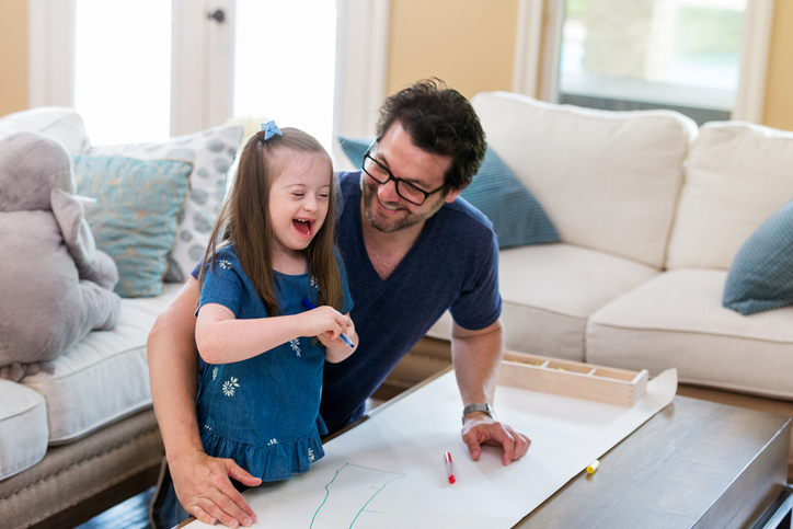 A father and daughter at a table coloring  