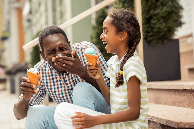 Dad eating ice cream with daughter and laughing