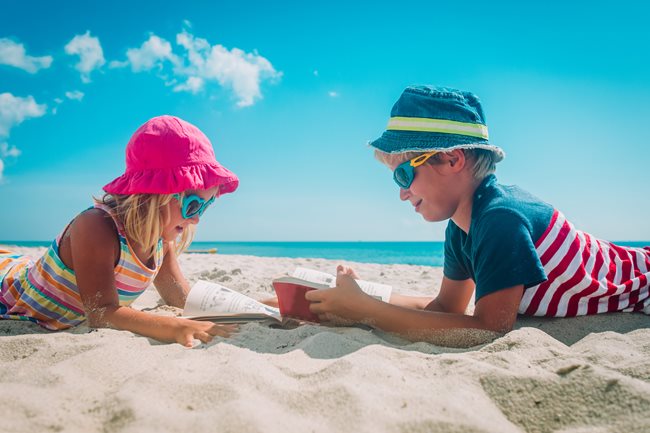 Boy and girl reading on the beach