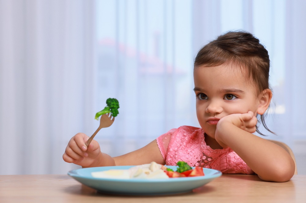Young girl refusing to eat her vegetables