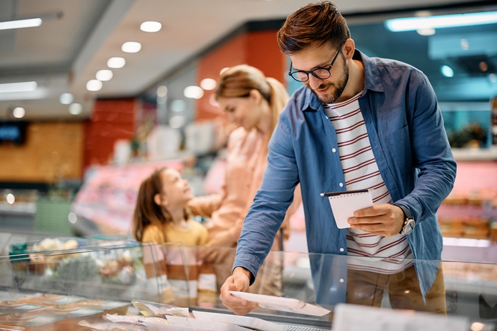 Dad picking our food in grocery store with mom and daughter behind him