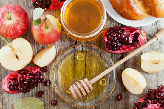 A platter of fruit with bowls of honey