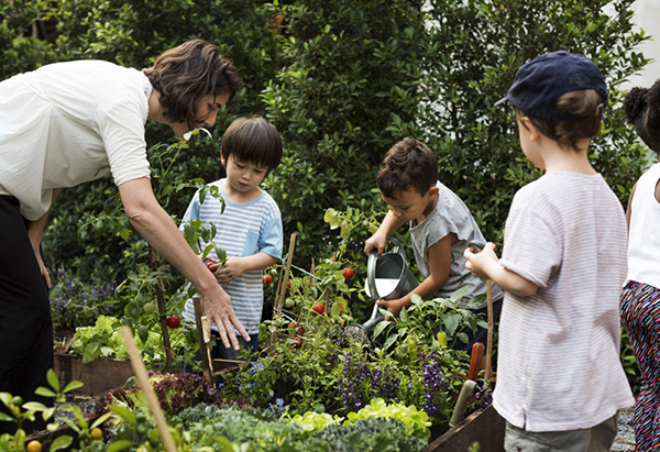 Teacher showing group of young kids how to garden