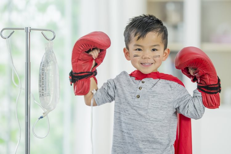 A boy in a hospital setting with an IV wearing boxing gloves and face paint as a boxer