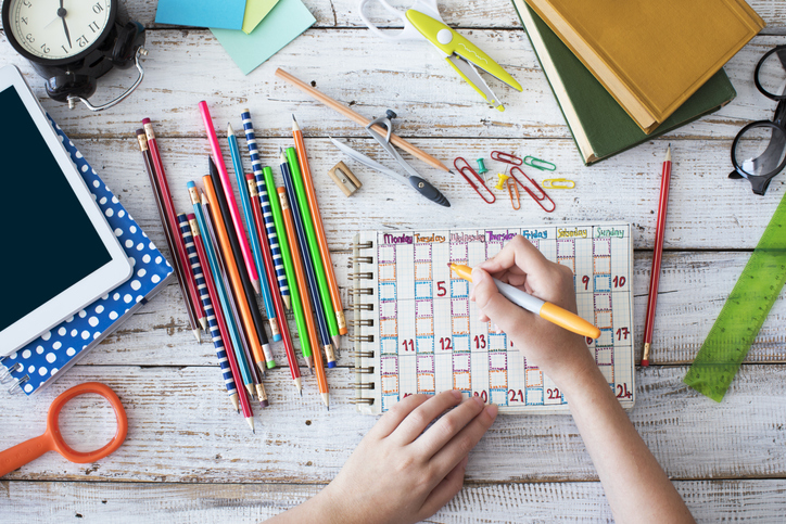 A child's desk with colored pencils and brightly colored paper 