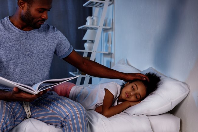 Dad tucking daughter into bed