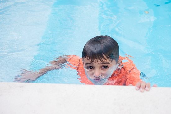 A child swimming with his lower face submerged in water