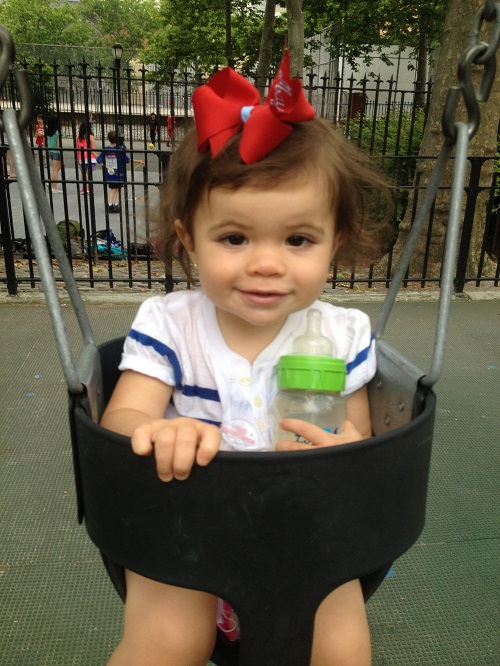 A little girl sitting in a park swing