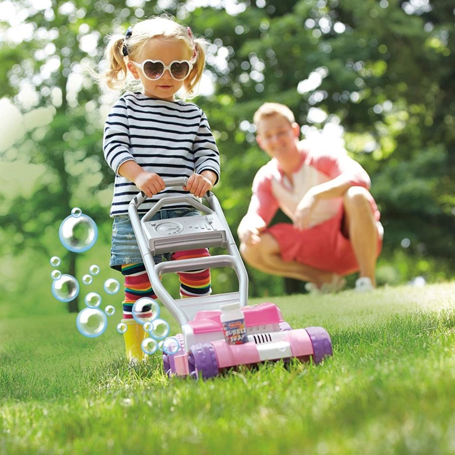 A little girl pushing a toy lawnmower