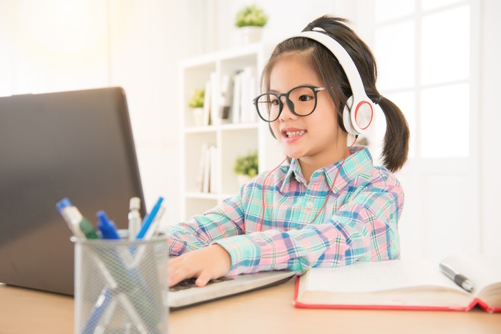 A young girl at a computer screen smiling 