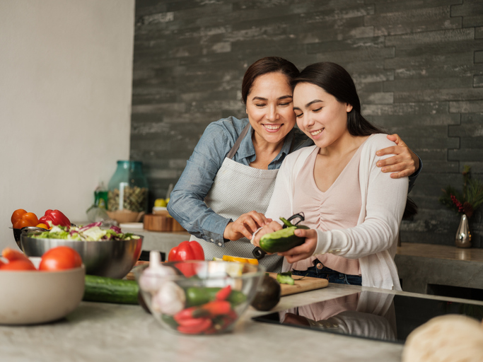 mother and daughter peeling vegetables in the kitchen.