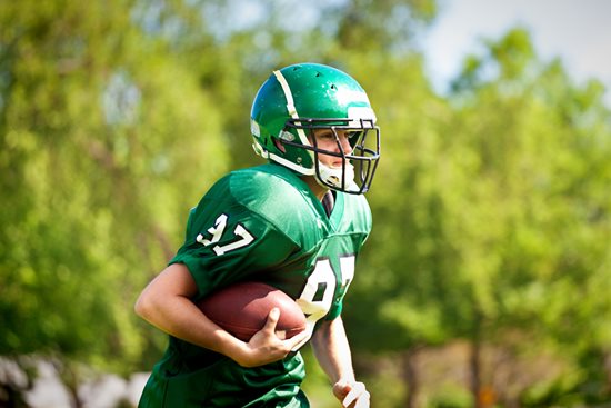 A youth tackle football player running with the ball