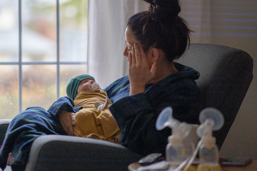 An exhausted mother holds her infant child wrapped in a blanket