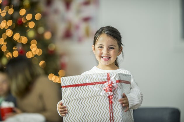 A small child smiling holding a present