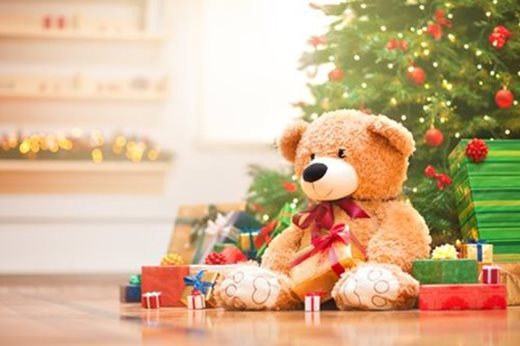 Teddy bear and gifts next to Christmas tree
