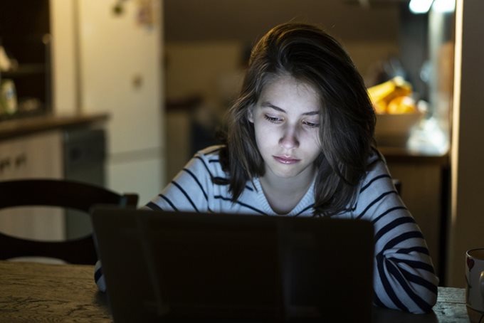 teen girl looking at laptop screen with worry.