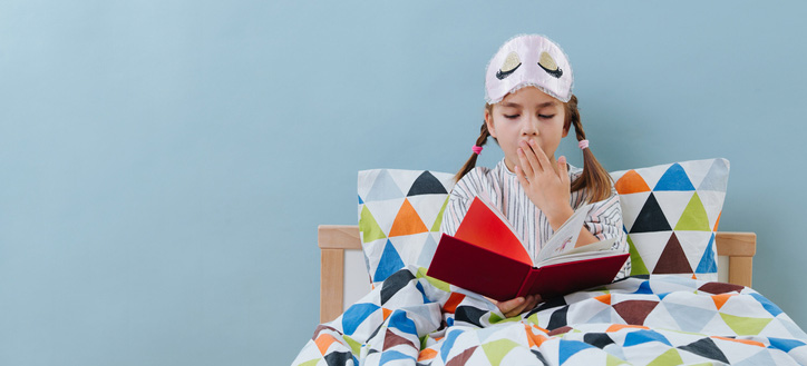 A young child in bed reading a book