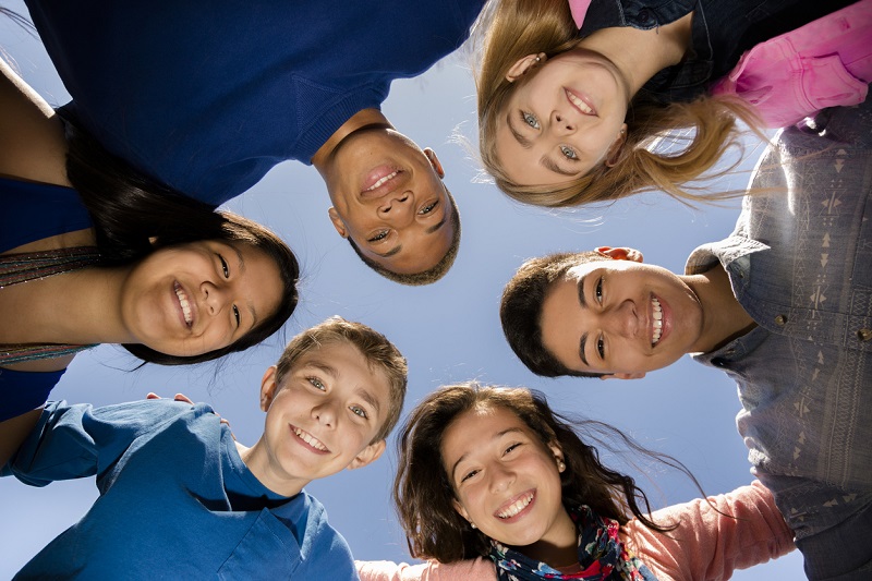 Group of diverse teens in a huddle, smiling