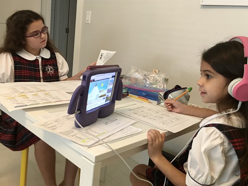 Two children at a desk looking at at a screen