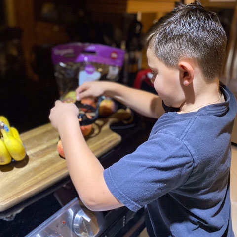 niño cortando una manzana con un rebanador de manzanas