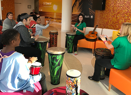 music therapy team playing bongos in a lobby area for patients.