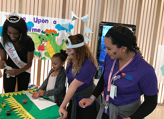 child life specialists and local beauty queen doing arts and crafts activity with a patient