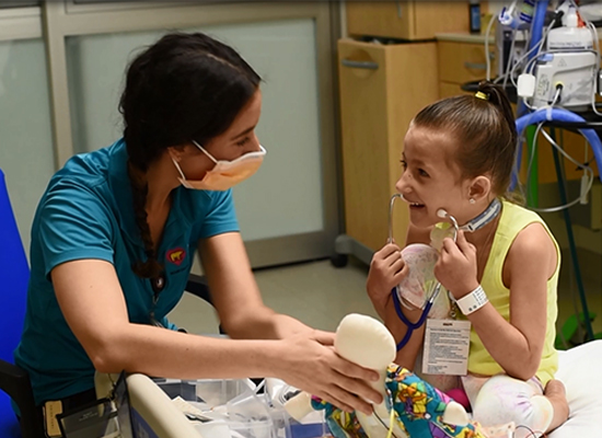 child life therapist playing with a tracheostomy patient on a doll.