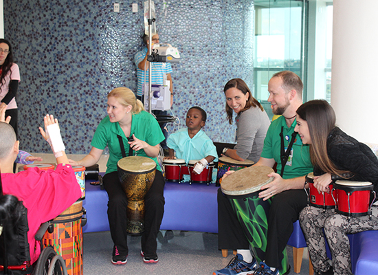 Therapists and children gathered in the lobby for a drumming session
