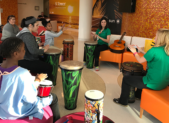 Therapists and children gathered in the lobby for a drumming session