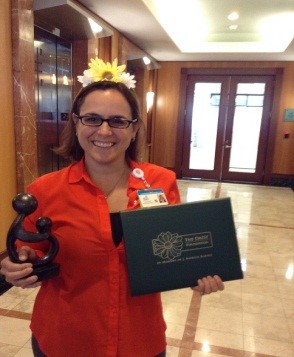 awardee wearing a headband of daisies, daisy award statue, and certificate.