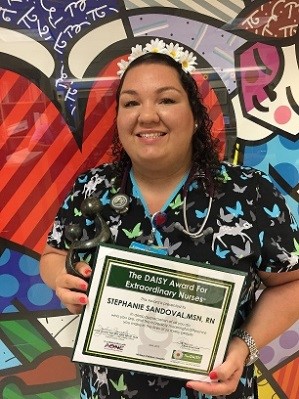 awardee wearing a headband of daisies, daisy award statue, and certificate.