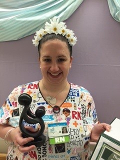 awardee wearing a headband of daisies, daisy award statue, and certificate.