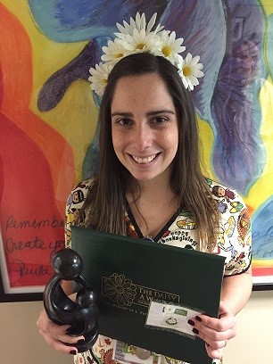 awardee wearing a headband of daisies, daisy award statue, and certificate.