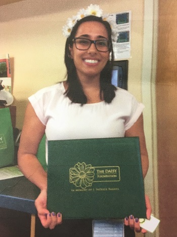 awardee wearing a headband of daisies, daisy award statue, and certificate.